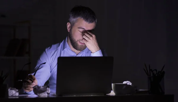 El hombre cansado está trabajando en el portátil en la oscuridad —  Fotos de Stock