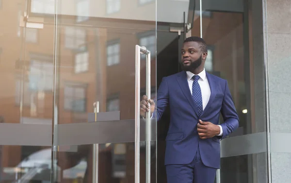 Confident african businessman walking out of modern office center — Stock Photo, Image