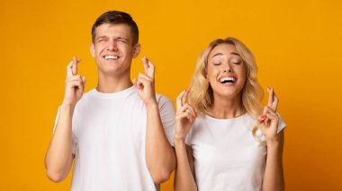 Genç adam ve kadın kapalı gözleri ile umut ile parmaklarını geçiş