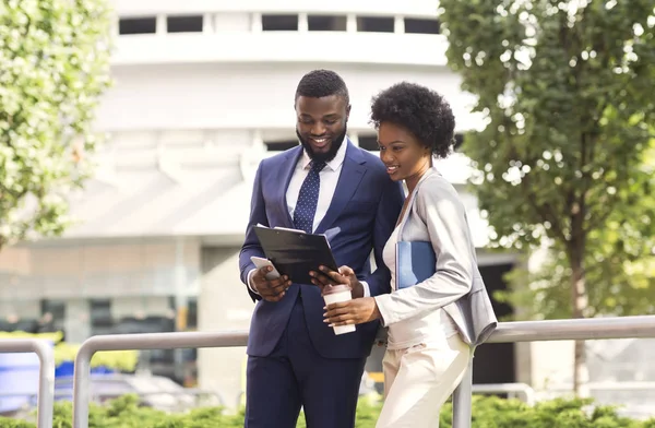 Deux collègues souriants noirs vérifiant les rapports financiers à l'extérieur, femme prenant un café — Photo