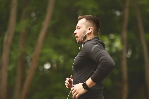 Mladý mužský sportovec v parku s joggesem — Stock fotografie