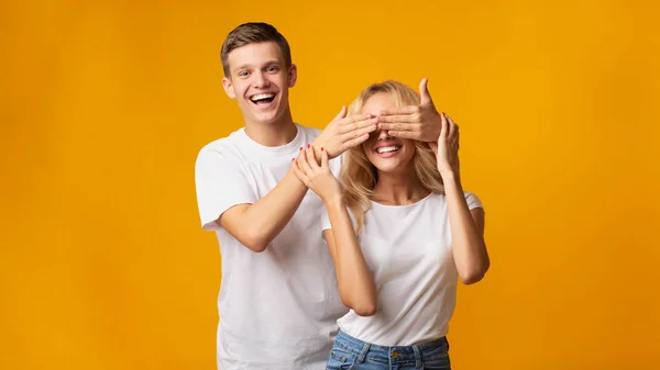 Young guy standing behind girlfriend and closing her eyes — Stock Photo, Image