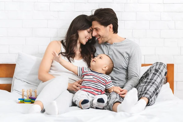 Couple millénaire amoureux embrasser sur le lit avec bébé curieux — Photo