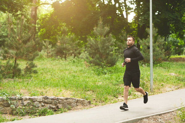 Молодой спортсмен бегает на беговой дорожке в парке
