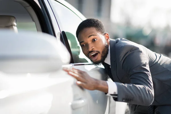 Visite concessionnaire automobile. Afro homme étreignant sa nouvelle voiture — Photo