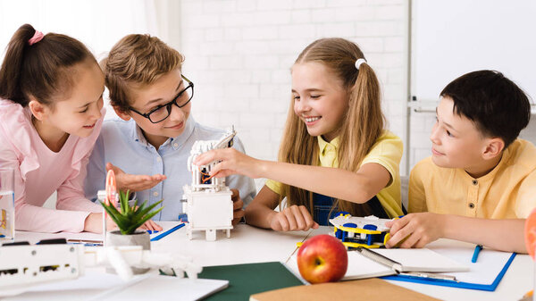 Счастливые дети, строящие роботизированные устройства на стебельном классе
