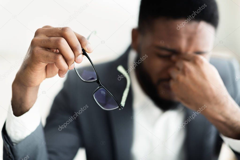 Tired african businessman taking his glasses off