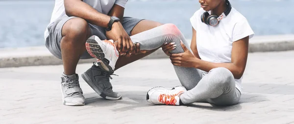 Hombre afroamericano ayudando a mujer con rodilla lesionada, recortado —  Fotos de Stock