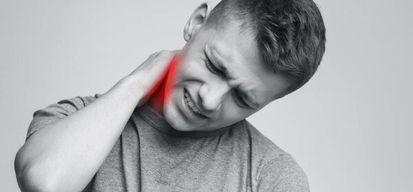 Young man feeling exhausted and suffering from neck pain