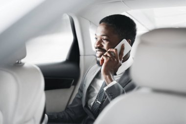 Mutlu afro işadamı arabada cep telefonu konuşuyor