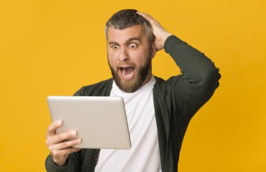 Tablet tutan ve kafasına dokunan etkilenen sakallı adam