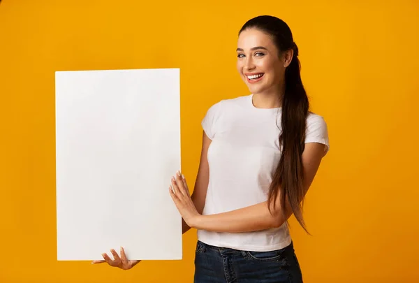 Jonge dame houden blank wit bord op gele achtergrond — Stockfoto