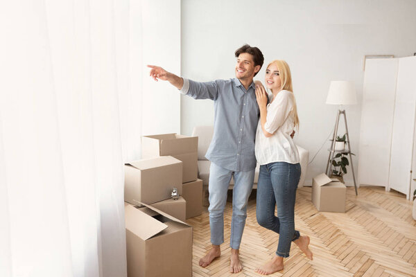 Cheerful Man Showing Woman View From Window Of New House