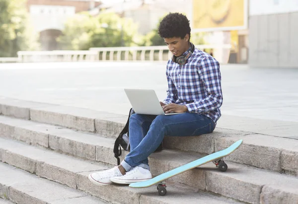 Genç erkek öğrenci dizüstü bilgisayar kullanarak açık havada stying — Stok fotoğraf