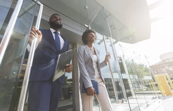 Confident african business people walking out of modern office center