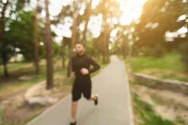 朝のジョギングの背景。都市公園で走っている男のぼやけたショット — ストック写真