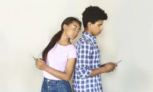 Svartsjuk Tonåring flickvän tittar på hennes pojkvän textning på telefon — Stockfoto