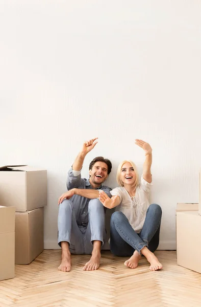 Casal animado sentado no chão discutindo o futuro design de interiores — Fotografia de Stock