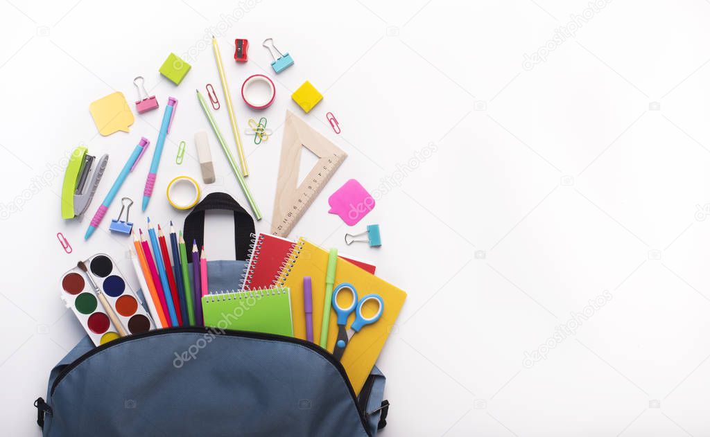 Open school backpack with stationery inside on white