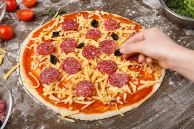 Ev yapımı pizza. Pizzaya siyah zeytin ekleyen kadın