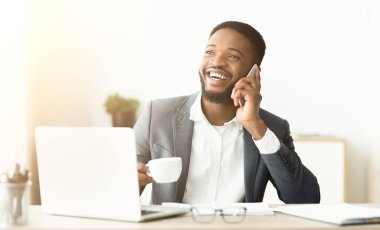 Kahve molası sırasında cep telefonuyla konuşan Afro-Amerikalı işadamı.