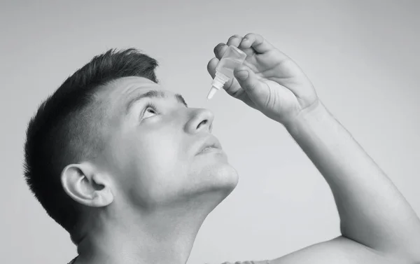 Homem aplicando oftalmologia conta-gotas, foto preto e branco — Fotografia de Stock