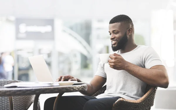 Αφρικανός Αμερικανός άνθρωπος που έχει το γεύμα στο καφέ και τη χρήση του φορητού υπολογιστή — Φωτογραφία Αρχείου
