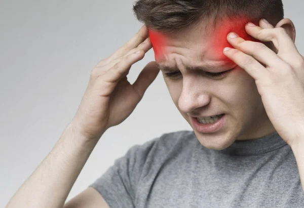 Akutní bolest hlavy. Mladý muž, který se dotýká jeho bolavé svatyně — Stock fotografie
