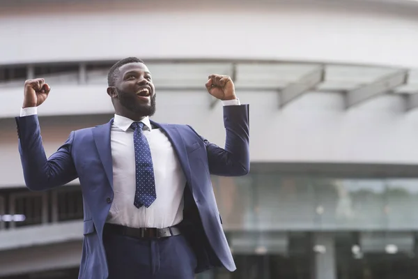 Glücklicher schwarzer Geschäftsmann feiert Sieg mit in die Luft gereckten Fäusten — Stockfoto