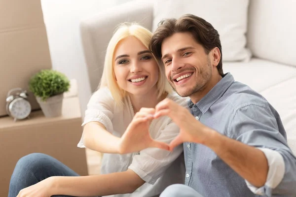 Pareja haciendo forma de corazón con sus manos en un nuevo hogar — Foto de Stock