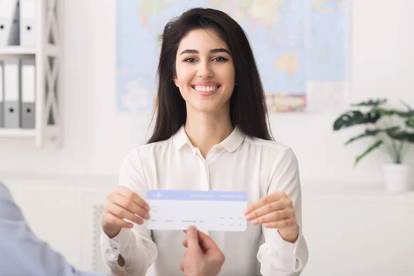 Happy travel agent showing flight ticket to customer