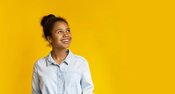 Menina pensativa olhando para cima no espaço vazio no fundo amarelo — Fotografia de Stock