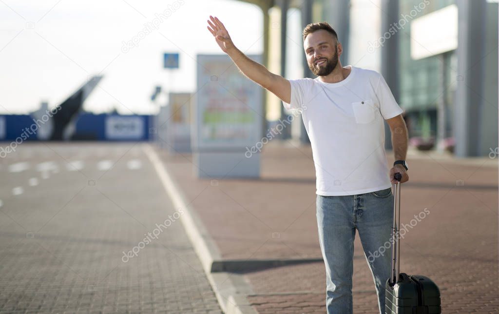 Man standing near airport, trying to catch taxi