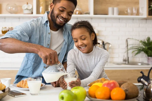 Negro padre verter leche en su hija taza —  Fotos de Stock