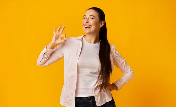 Aufgeregtes Mädchen gestikuliert ok Zeichen auf gelbem Studiohintergrund — Stockfoto