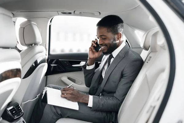 Empresário afro organizando seus assuntos no carro — Fotografia de Stock