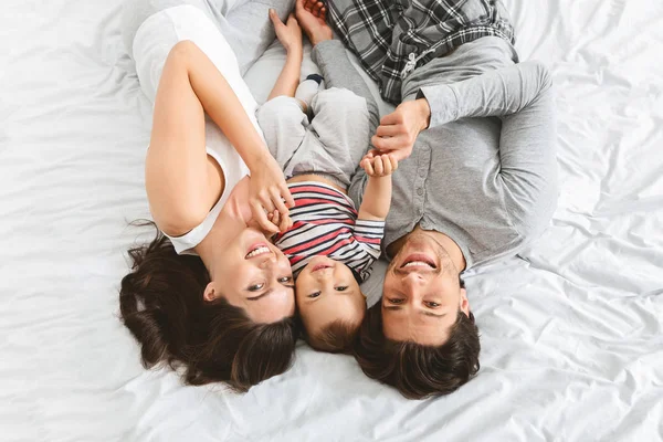 Acariciar família positiva na cama com o bebê filho — Fotografia de Stock