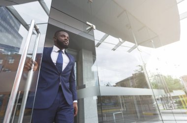 Kendine güvenen Afrikalı işadamı modern ofis merkezinden çıkıyor