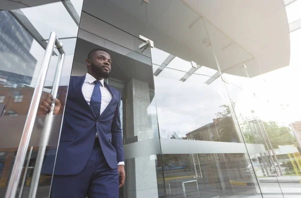 Confident african businessman walking out of modern office center — Stock Photo, Image