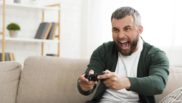 Мужчина средних лет играет в видеоигры дома — стоковое фото