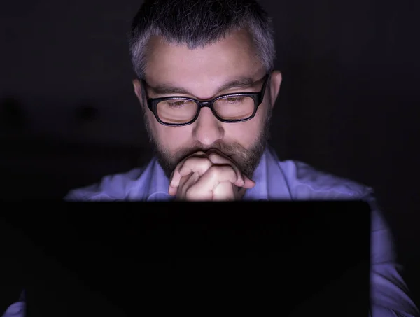 Προβληματισμένος άνθρωπος κοιτάζοντας την οθόνη του φορητού υπολογιστή σε σκοτεινό δωμάτιο — Φωτογραφία Αρχείου