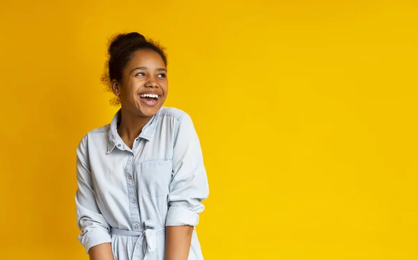 Aufgeregter schwarzer Teenager blickt vor gelbem Studiohintergrund nach oben — Stockfoto