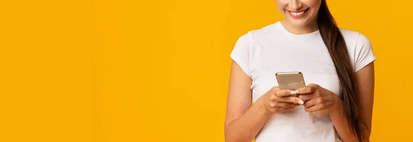 Millennial Girl mit Handy auf gelbem Studiohintergrund, beschnitten — Stockfoto