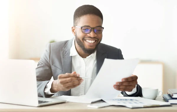 Hombre de negocios afroamericano guapo trabajando en documentos de lectura de oficina —  Fotos de Stock