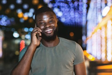 Gece şehir yürürken telefonda konuşan Afro adam