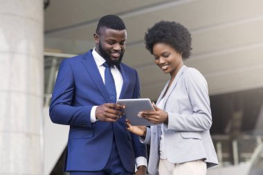 Dijital tablet kullanan ve açık havada yeni proje yi tartışan iş adamları