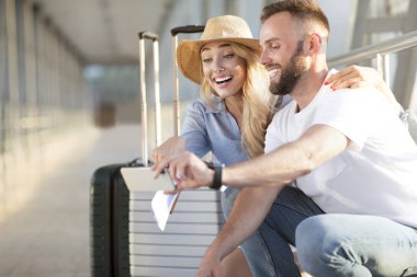 Akıllı telefon kullanarak havaalanında heyecanlı çift, gezi arıyor