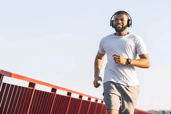 Usmívající se africký Američan, který běží po mostě — Stock fotografie
