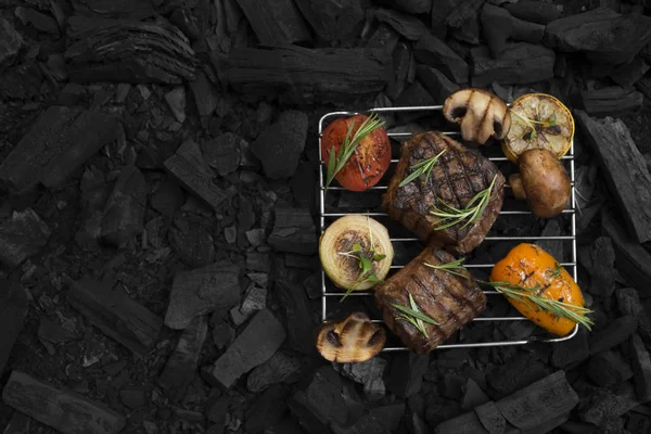 Grilled meat steaks with vegetables on grid prepared on coal — Stock Photo, Image