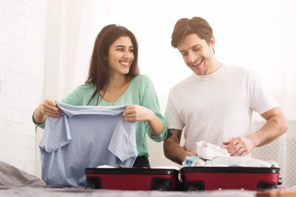 Pareja feliz preparándose para la luna de miel, doblando la ropa — Foto de Stock